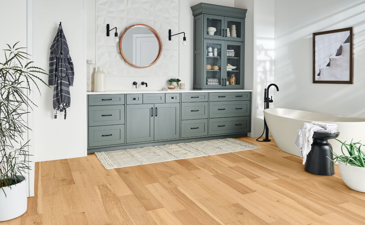 hardwood flooring in bathroom with green cabinetry.